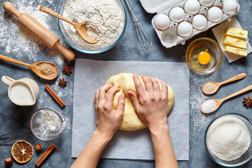 Baker knead dough bread, pizza or pie recipe ingridients with hands, food flat lay on kitchen table...