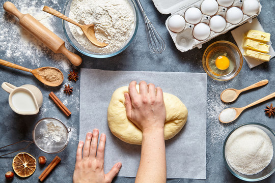 Baker mixing dough bread, pizza or pie recipe ingridients, food flat lay on kitchen table background. Hands working with butter, milk, yeast, flour, eggs, sugar pastry or bakery cooking.
