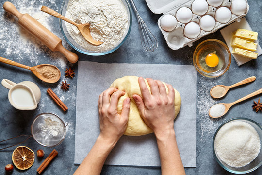 Baker knead dough bread, pizza or pie recipe ingridients with hands, food flat lay on kitchen table background. Working with butter, milk, yeast, flour, eggs, sugar pastry or bakery cooking.