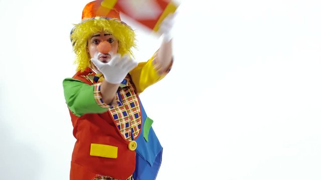 Funny clown walking backward showing colorful box and smiling in surprise