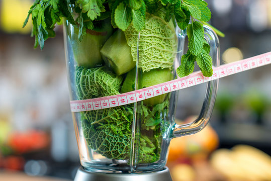 Close Up View On The Blender Full Of Green Fruits And Vegetables Ready To Mix With Meter In The Kitchen. Healthy Vegetarian Diet For Weight Loss And Detox