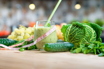 Glass with smoothie with green vegetables on the table in the kitchen. Healthy vegetarian diet for weight loss and detox
