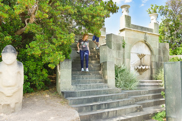 Tourists descend the stairs near the wall fountain "Shell" in the southern part of the Park of the Vorontsov Palace. Yalta, Alupka, Crimea, Russia