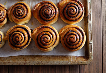 Freshly baked cinnamon rolls buns with cocoa and spices on a metal a baking sheet. Close-up. Kanelbulle - swedish pastry dessert. Christmas baking pastry.