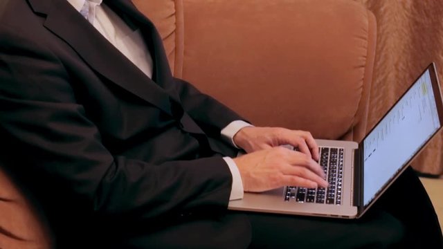 Man typing while sitting on the sofa.