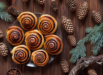 Sweet Homemade christmas baking. Cinnamon rolls buns with cocoa filling. Kanelbulle swedish dessert. Festive decoration with pine cones and Christmas tree