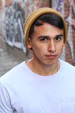 Close up portrait of a young man with beanie and piercing or nose ring