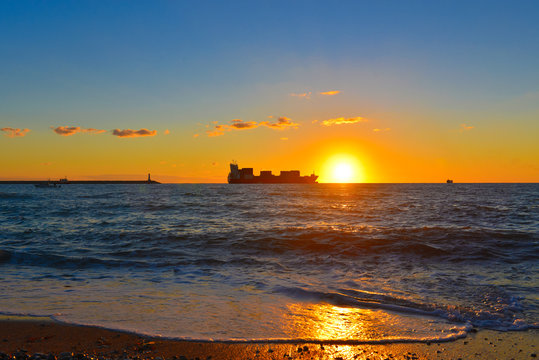 Cargo ship in sunset sea