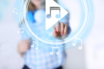 Woman pushing PLAY button on virtual screen to launch music player, closeup