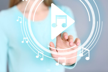 Woman pushing PLAY button on virtual screen to launch music player, closeup