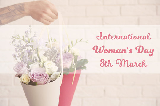 Male hand holding beautiful bouquets. Text INTERNATIONAL WOMAN'S DAY, 8TH MARCH on background