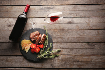 Grilled steak and appetizers with wine on wooden table