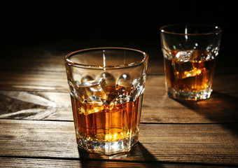 Glasses of whisky on wooden table closeup