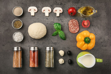 Raw dough for pizza with ingredients and spices on table