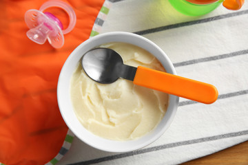 Bowl with healthy baby food on table. Child feeding concept