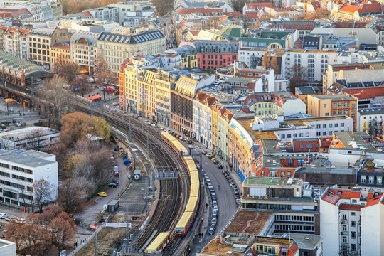 Beautiful panoramic aerial view over Berlin down onto S-Bahn tracks (rapid train) and colorful buildings at sunset.