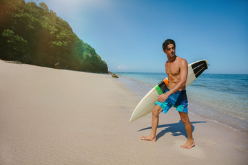 Obraz premium Male surfer holding surf board walking out of the sea