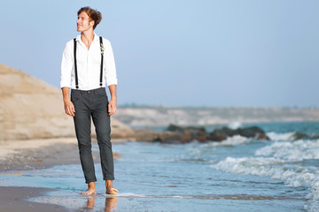 Young man walking along seashore