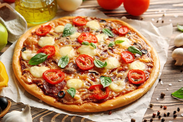 Fresh pizza with tomatoes, cheese and mushrooms on wooden table closeup