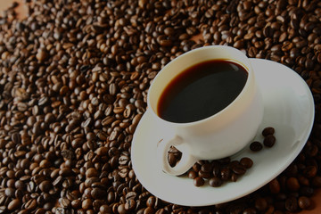 Cup of coffee on beans as background