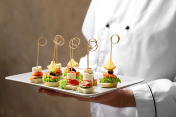 Fototapeta na wymiar Chef holding plate with assorted canapes closeup