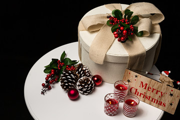 Decoración navideña con merry christmas,  caja de regalo y velas en mesa.