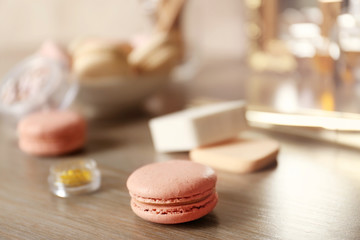 Tasty macaroons and beauty accessories on table