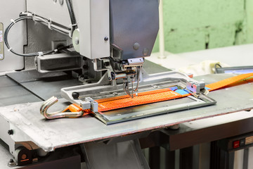 Industrial sewing machine sews a ratchet strap.