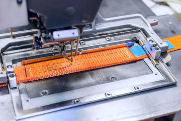 Industrial sewing machine sews a ratchet strap. - obrazy, fototapety, plakaty