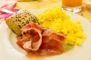 Scrambled eggs with bacon and bread with seeds