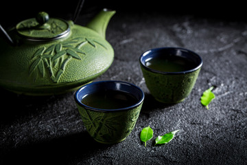 Green tea with teapot and cup on black rock
