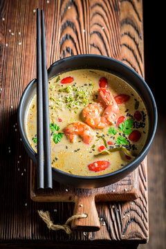 Delicious Tom Yum soup in black bowl with chopsticks