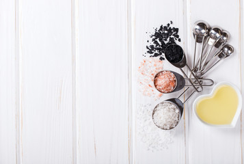 Salt,white,black,pink measuring spoons on a white Background and olive oil.classic spice for cooking. top view. Copy space. selective focus.
