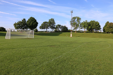 A view of a net on a vacant soccer pitch in morning light..