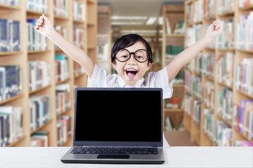 Cheerful child with empty laptop screen in library