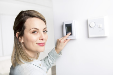 woman set the thermostat at house.