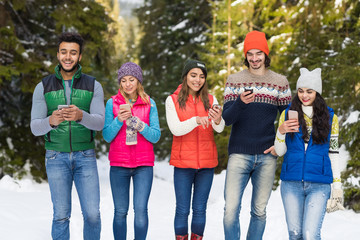 Fototapeta premium People Group Using Smart Phone Chatting Online Snow Forest Happy Smiling Young Friends Walking Outdoor Winter Pine Woods