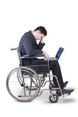 Stressful businessman with wheelchair and laptop