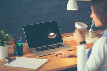 Portrait relaxed young woman sitting at her desk holding cup of coffee