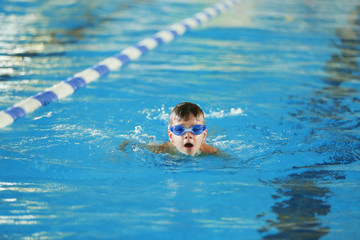 Cute boy training in sport swimming pool