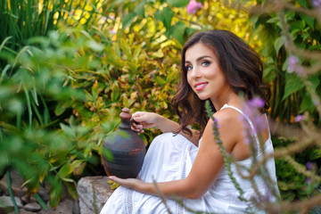 Obraz premium Lovely girl in a white dress holding a little old pitcher.
