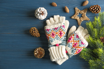 Knitted mittens and decor on wooden background