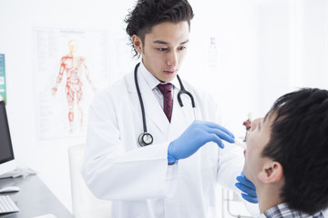 A young man is undergoing a throat exam