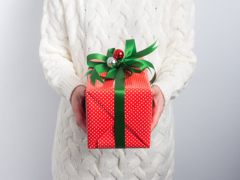 Celebrate the new year 2017.Close up shot of female hands holding a gift box and nice ribbon. Gift box color  in the hand of a woman wearing a knitted hat sweater on white  background.