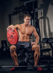 Fototapeta na wymiar Muscular man holds barbell weight in a gym club.