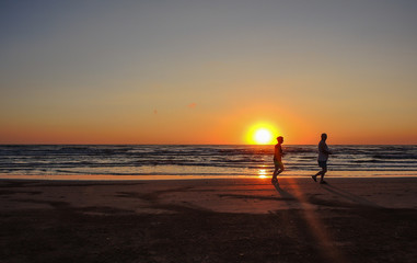 People are running at the sunrise on the beach. Silhouette. Italian coast. Emilia Romagna. Italy