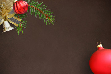 Christmas fir branch, red wavy dull ball and bell on a dark background