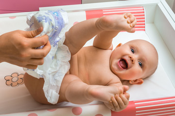 Mother changing diaper to her little baby girl