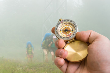 Traveler man with compass seeking a right way through the fog