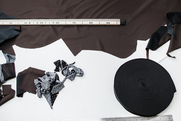 Pattern cutting designer workplace flat lay. Top view on tailor table with dark fabric, measuring...